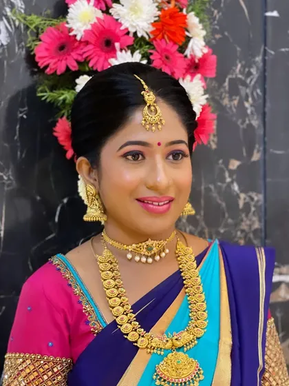 Kavya looking radiant for her housewarming ceremony. A classic look with a bright, colorful saree and traditional gold jewelry.