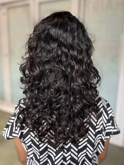 A beautiful example of a curly haircut done by one of our students on a real model, enhancing the natural curl pattern and adding shape.