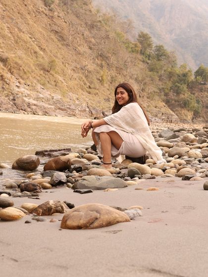 A quiet moment of reflection by the Ganga river. The riverbank, with its smooth stones and gentle sounds, becomes our sanctuary for meditation and connection.