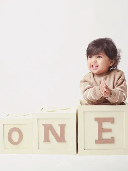 Clapping with glee! This happy baby celebrates turning one with classic wooden blocks in a clean, minimalist studio setup.