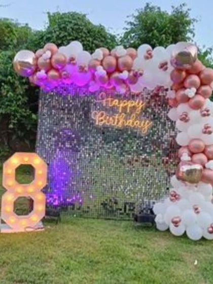An outdoor 18th birthday party with a silver sequin wall. The rose gold and white balloon arch and large marquee numbers create a stunning evening look.