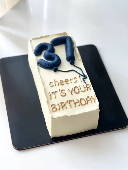 A minimalist and modern loaf cake with "31" balloon toppers. A chic way to celebrate a birthday.