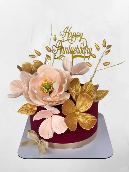 Anniversaries deserve a touch of drama. This deep red velvet cake is adorned with oversized, handcrafted sugar flowers in shades of pink and gold for a truly memorable statement.