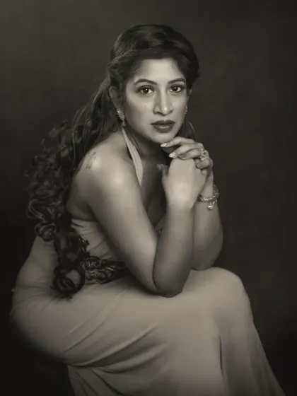 A powerful and poised monochrome portrait of Pallavi. Her hands are clasped as she looks directly at the camera, her expression conveying both strength and vulnerability. The dramatic lighting sculpts her features, creating a truly classic fine art image.