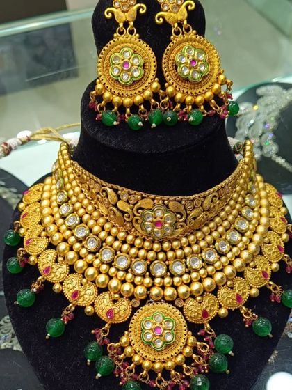 A beautiful gold-look choker set with meenakari work in the center and green bead drops. This piece has a very authentic, traditional feel.