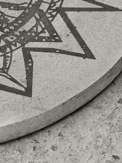 A detail of the edge of the concrete art table, showing the smooth, hand-finished curve of the tabletop.