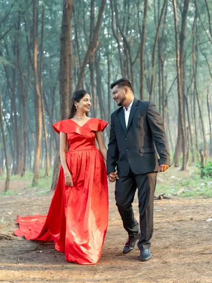 A happy couple walks hand-in-hand through a wooded path, a beautiful shot from their nature-themed pre-wedding session.