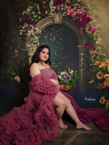 A solo portrait of the mother-to-be in a dramatic ruffled gown, seated and holding a basket of flowers. This shot is full of texture and color.