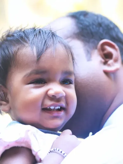 A father holding his daughter close, both of them sharing a happy smile. This image radiates warmth and the special bond between a dad and his little girl.