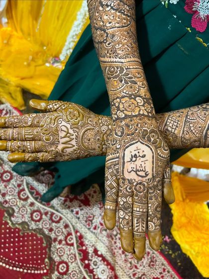 A beautiful bridal design that includes the names of the bride and groom written in elegant Arabic script on the palms.