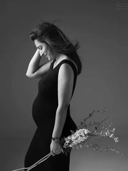 A candid smile and a simple prop. Holding flowers adds a touch of softness to this beautiful black and white side-profile portrait.
