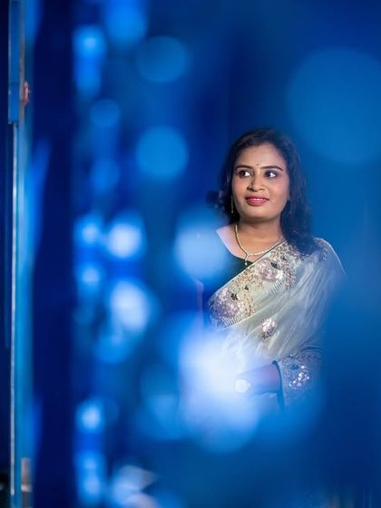 An artistic shot using a foreground blur to create a sense of looking in on a private moment. The blue background adds a pop of color and style.