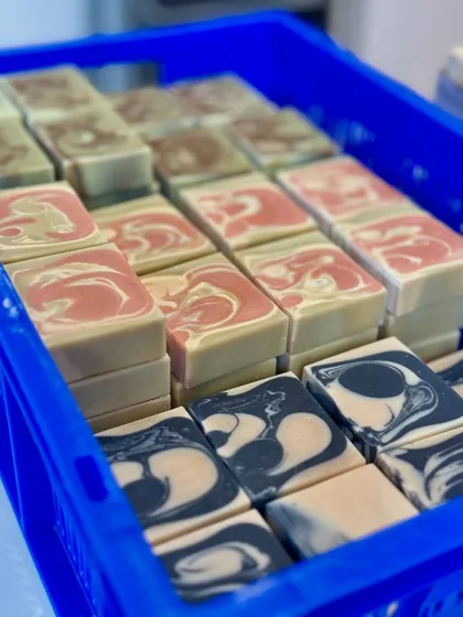 Another view of our curing soaps. The vibrant colors and unique swirls are a testament to the handmade nature of our products. Each batch is slightly different, making every bar special.