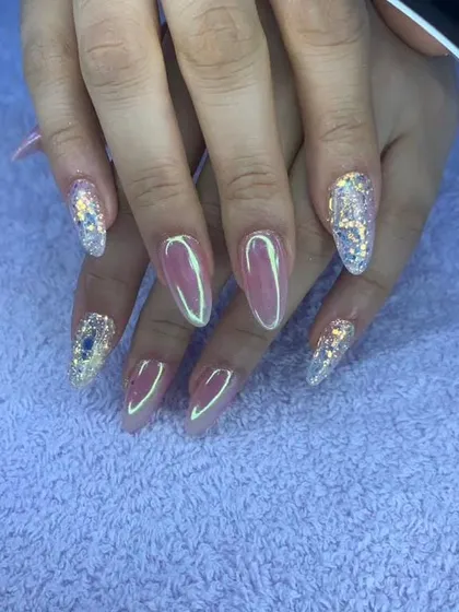 A glamorous set of stiletto nails with a mix of pink chrome and encapsulated glitter.