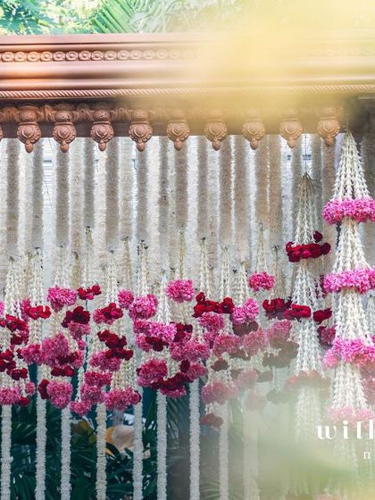 A close-up of the floral backdrop for a summer wedding, featuring strings of tuberose accented with clusters of pink and red oleander. The design is both traditional and refreshingly modern.