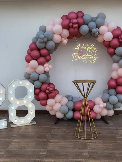 Celebrating a 28th birthday in style. This outdoor terrace setup features a modern balloon ring in pastel and grey, a custom neon sign, and large marquee numbers. It’s a chic and trendy way to mark a milestone birthday.