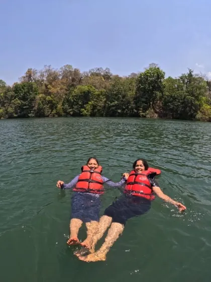 Two trekkers floating peacefully in the Kali river, wearing life jackets for safety.
