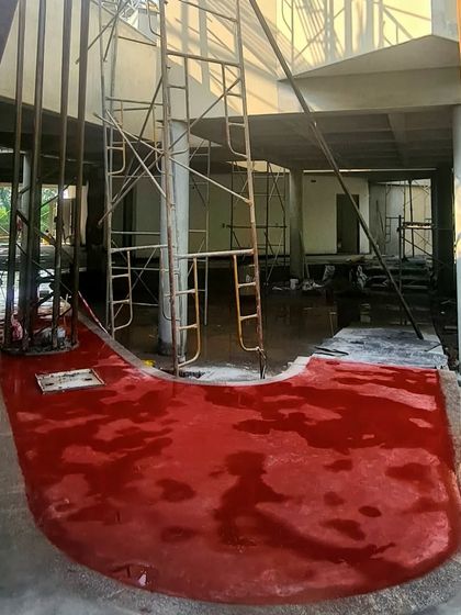The initial application of red oxide flooring at the TAPMI Centre, a moment where the project's core material identity begins to emerge.