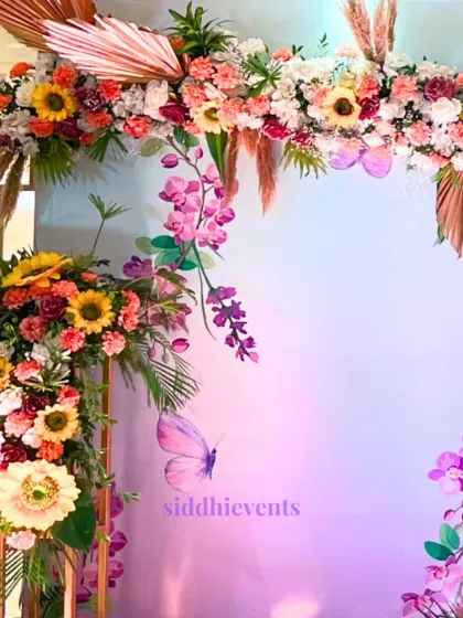 Detail of the floral arch, highlighting the combination of bright sunflowers, pink orchids, and dried palm leaves for a modern yet festive Haldi look.