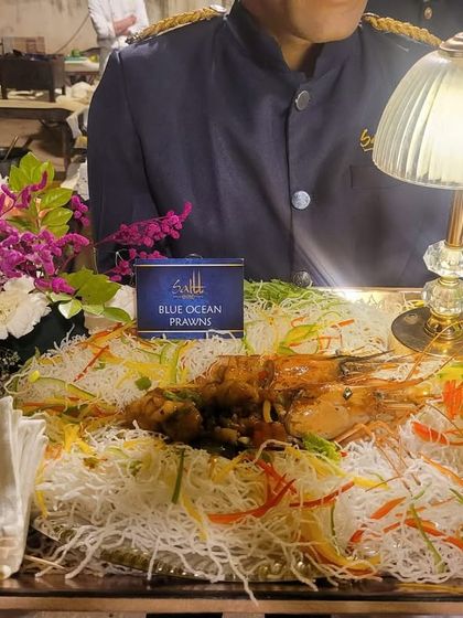 A magnificent platter of Blue Ocean Prawns served on a bed of glass noodles and fresh vegetables. The presentation, complete with a table lamp, turns this dish into a centerpiece.