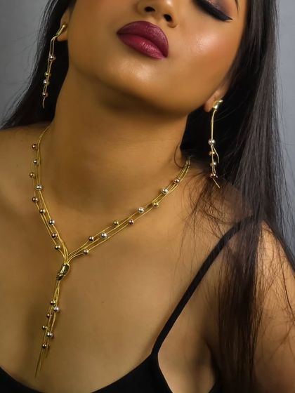 A sleek and modern gold chain necklace with matching drop earrings. This designer piece is perfect for power photoshoots or adding a bold touch to a simple outfit.