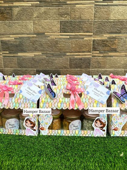 A butterfly and fairy princess theme hamper in a colorful cardboard box, filled with three jars of healthy snacks.