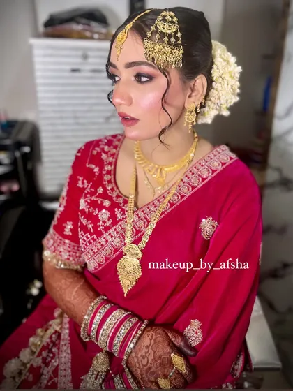 A simple yet stunning look for a bride in a red saree. The makeup is clean and elegant, with a focus on glowing skin and beautifully defined eyes, complemented by a white flower gajra in her hair.