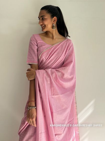A smiling model in our pink Karghewale saree. The combination of stripes, checks, and silver zari makes this a joyful and elegant piece.