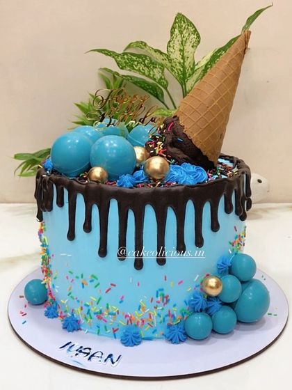 A blue Candyland themed cake for a baby boy's first birthday. This 3kg vanilla fresh fruit cake is decorated with a chocolate drip, an ice cream cone, and colorful sprinkles.
