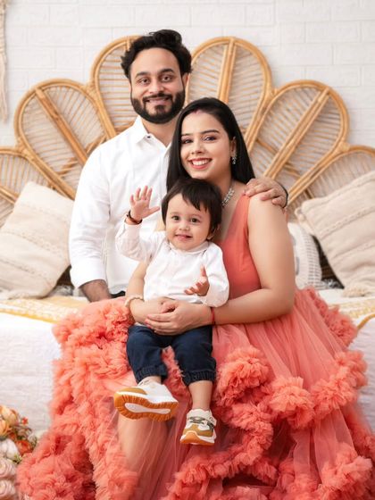 A perfect family portrait, full of smiles and warmth. The ruffled dress on the mother adds a touch of high-fashion elegance to the scene.