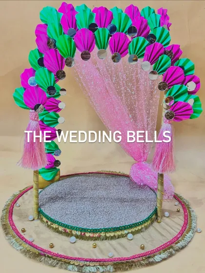 This Ganesha mandap design features a shimmering pink sequin backdrop, perfectly complementing the vibrant paper fan arch. It's a festive and glamorous choice for your Ganesh Chaturthi celebrations.