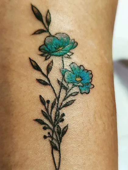 A close-up of a delicate floral tattoo. I used a mix of fine black lines for the stem and leaves, with a pop of turquoise blue for the flowers to create a beautiful contrast.