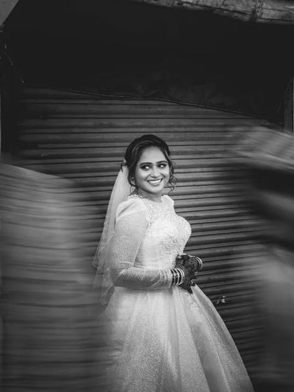 An artistic black and white bridal portrait using a slow shutter speed to create motion blur. The bride remains in sharp focus amidst the moving city.
