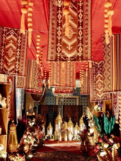A detail shot of the hanging rug installation, showing the variety of patterns and the warm glow from the chandeliers.