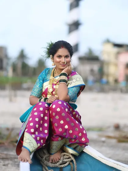 A beautiful portrait of the model sitting on a boat, embodying the spirit of the Koli fishing community. The makeup is traditional and enhances her strong features.