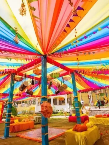 We love bringing energy to pre-wedding functions. This is a Mehendi setup we designed, featuring a vibrant canopy of multi-colored drapes, traditional hanging decor, and comfortable floor seating for a festive and joyful atmosphere.