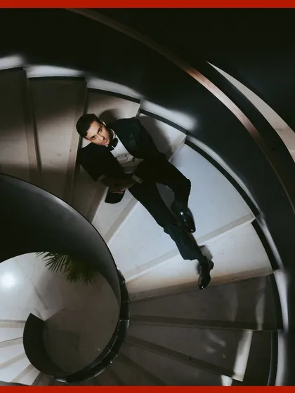 A creative perspective for a groom's portrait. This top-down shot on the spiral staircase creates a dynamic and artistic composition, showcasing his dapper tuxedo.