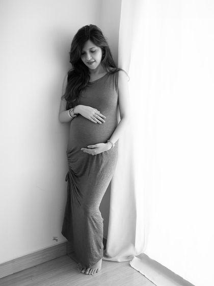 A full-length view showing the simple elegance of this grey dress. The clean lines and soft light make for a classic and minimalist maternity photo.