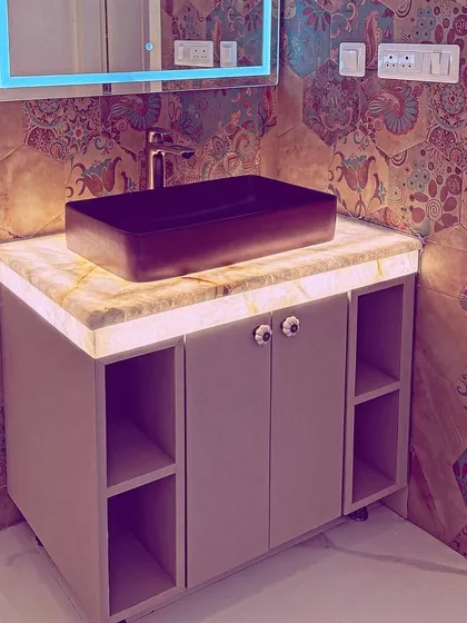 A vanity counter with a backlit onyx top and patterned Indian motif tiles, blending luxury with eco-friendly materials.
