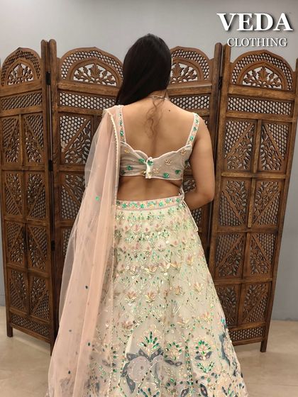 The back view of the pastel green lehenga, highlighting the stylish back design of the blouse and the delicate net dupatta.