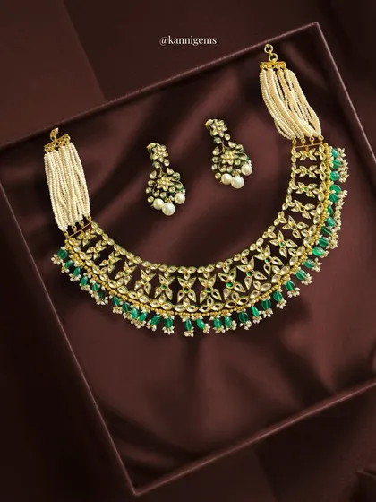 Luxury finds its true form in this intricately handcrafted Kundan choker. It blends rich textures of pearls, gleaming kundan work, and vibrant emerald drops, creating a statement of grace, tradition, and timeless beauty.