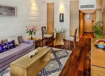 Another view of the Taj Vivanta Goa suite, highlighting the rich wooden flooring and the contemporary furniture. The design blends shades of purple and mushroom with natural textures to create a fresh and vibrant space.