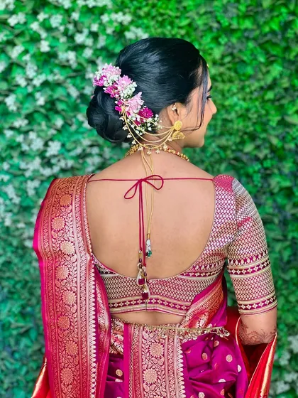 A detailed shot of Ramaa's bridal bun, adorned with fresh flowers and a traditional ear chain.