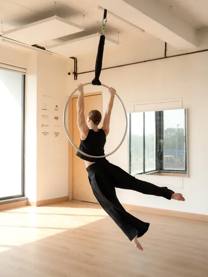 This image captures the feeling of flight on the aerial hoop. The flowing pants add to the sense of movement, showing how even simple poses can be dynamic and expressive.