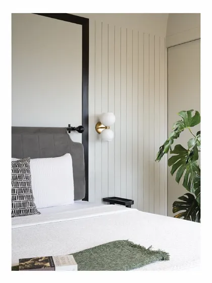 Bedside corners are opportunities for thoughtful details. In our Powai House project, a modern brass and glass wall sconce is mounted on a vertically paneled wall, providing soft, ambient light next to the upholstered headboard. It’s a small detail that adds a touch of elegance.