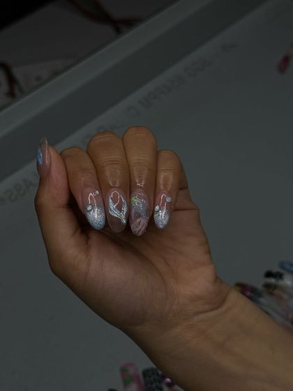 A close-up of the glistening silver nails, highlighting the combination of glitter and 3D art.