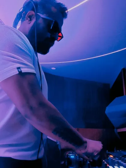 Lost in the rhythm, found in the lights. A candid shot of me mixing in a club with intense purple and blue lighting, completely focused on the next track.