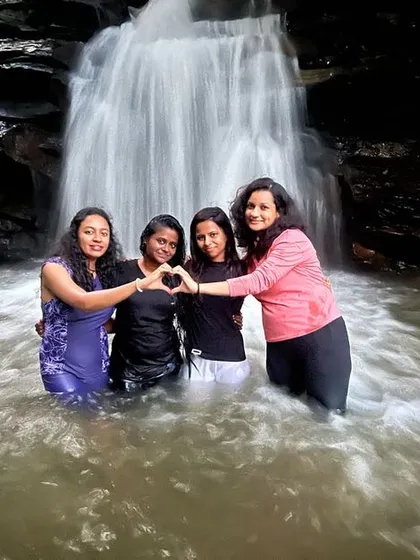 Four friends making a heart shape while enjoying a dip in a natural pool on the Netravathi trek.