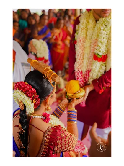 A detailed shot of a South Indian wedding ritual, focusing on the bride's hands and traditional elements.
