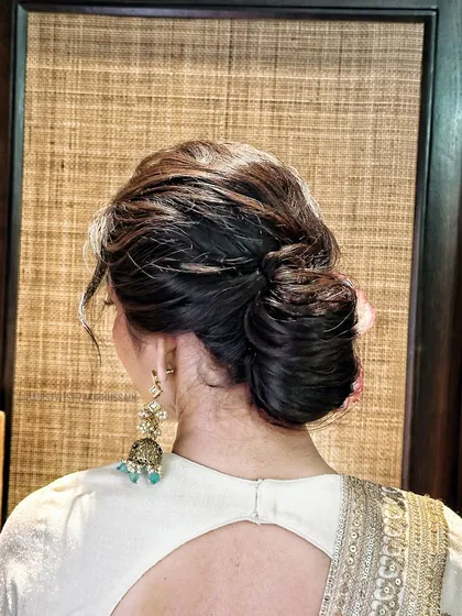 A close-up of a textured, messy bun, showing the intricate weaving and soft finish. This is a popular choice for a modern, relaxed bridal or party look.